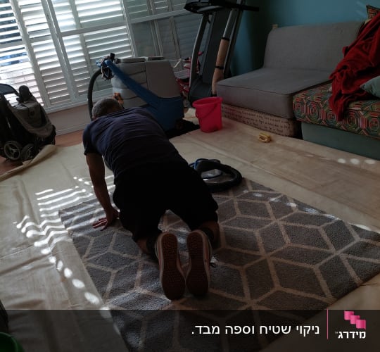 אדם מנקה שטיח עם מכונת ניקוי